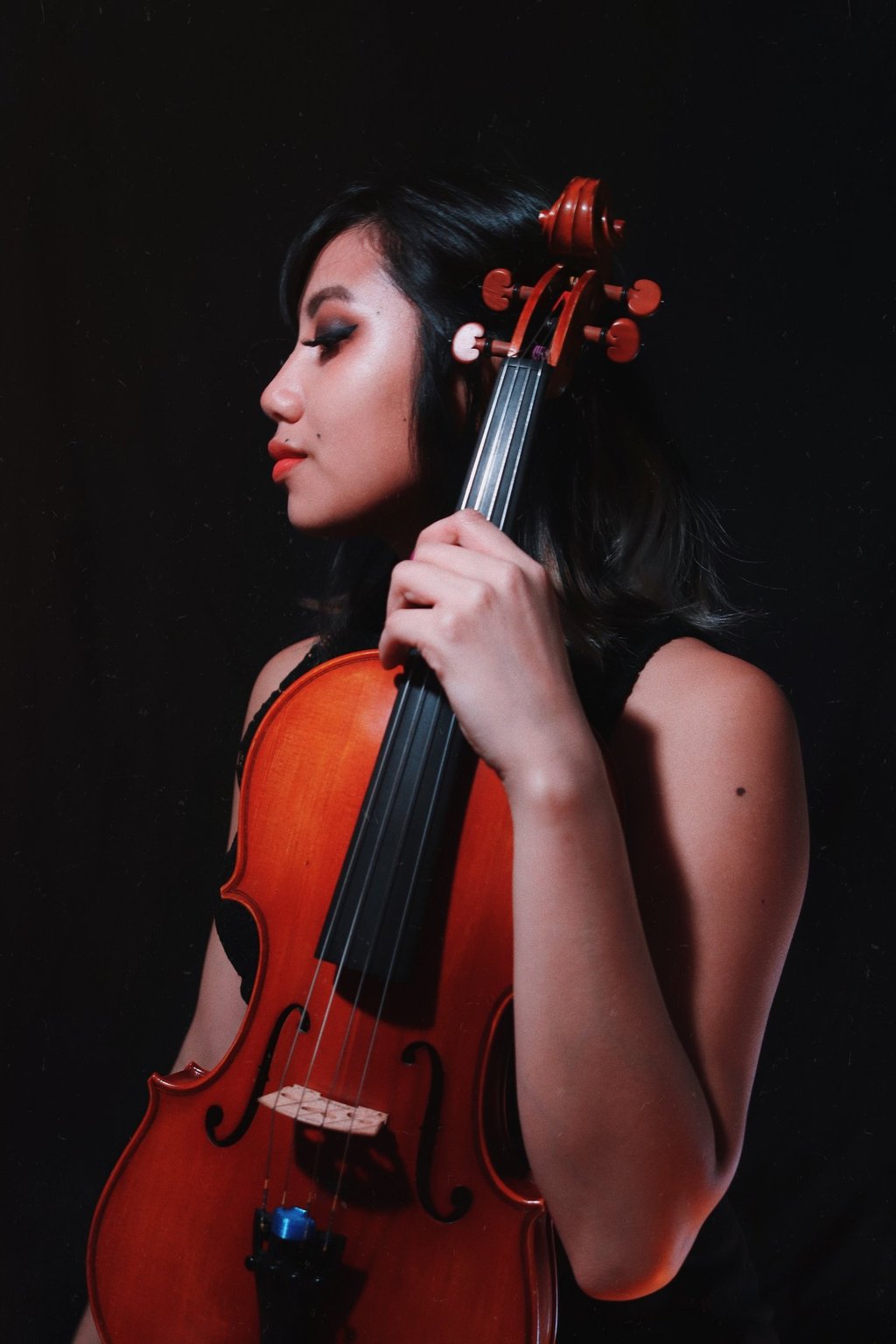 A professional self portrait holding a viola against a black backdrop. 