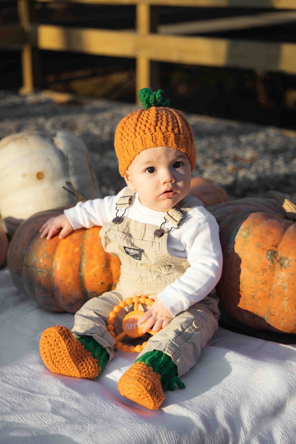 Super cute photo of baby boy in a pumpkin patch, dressed as a pumpkin.