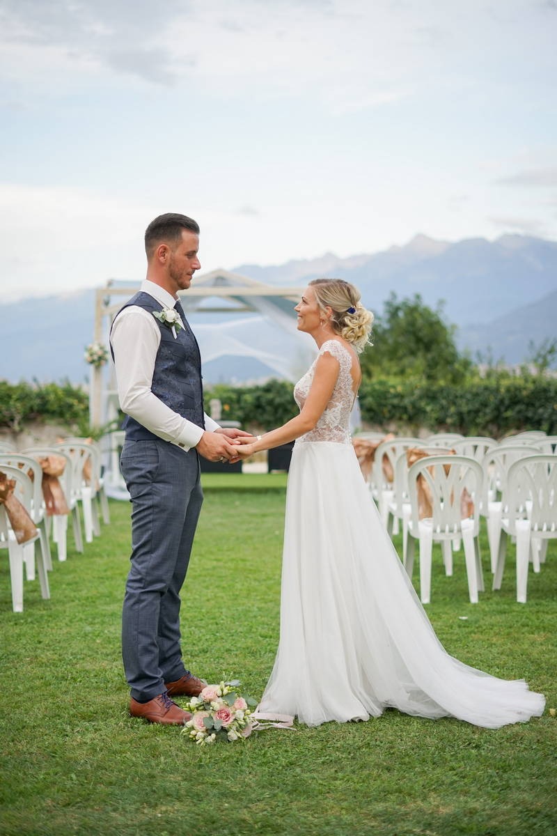 Photo d'un couple de mariés face à face se tenant la main sur le lieux de leur cérémonie de mariage
