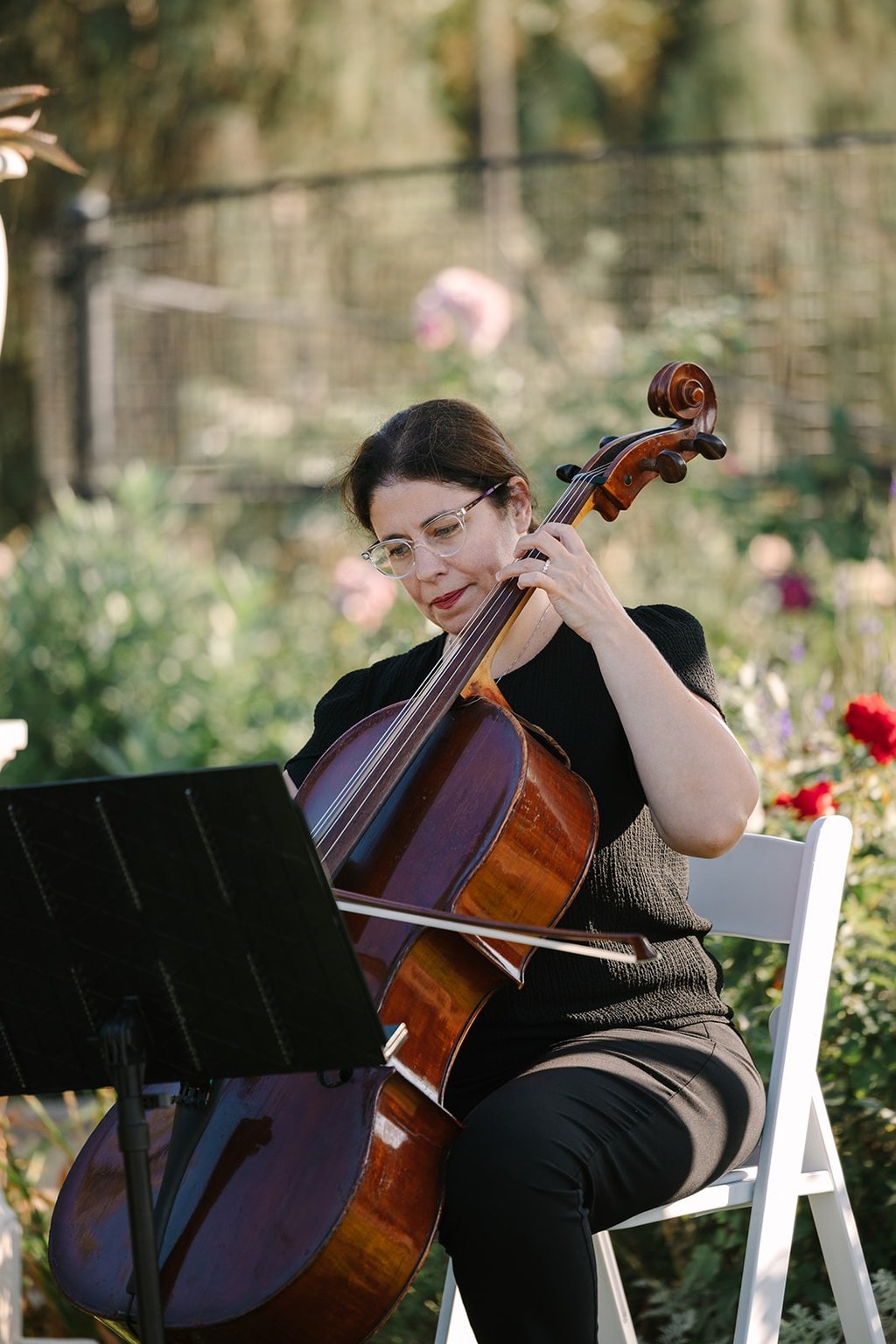 Professional cellist playing cello during an outdoor garden wedding ceremony.
