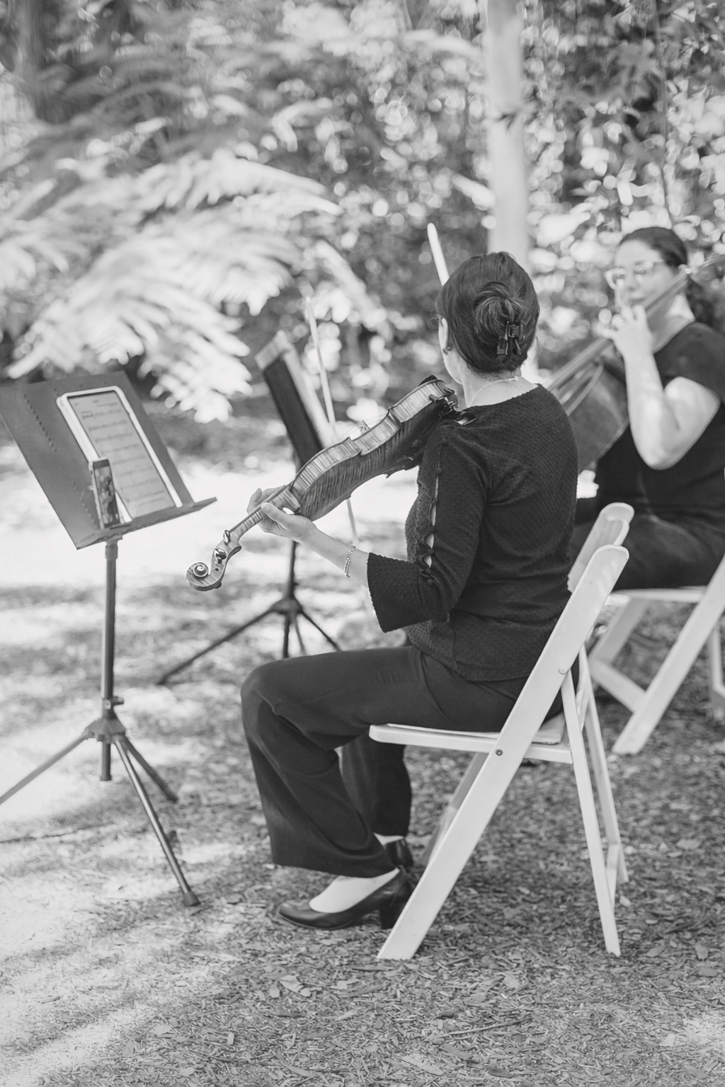 Violinist and Cellist perform at outdoor ceremony in a garden