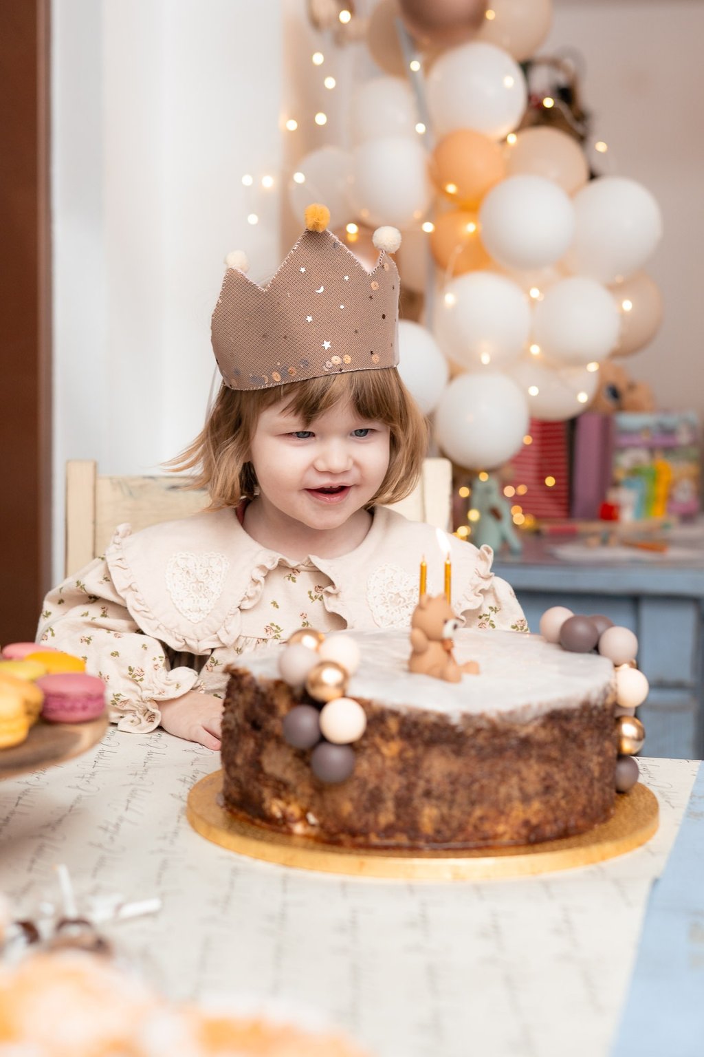 mala djevojčica sjedi za stolom i puše svijeće na torti