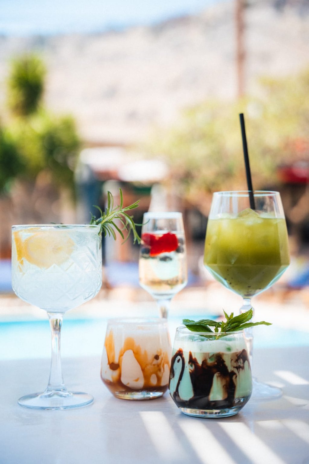 Assorted summer cocktails and refreshing iced drinks served poolside at a tropical resort.