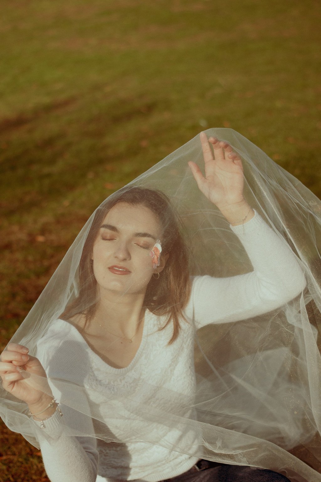 plan éloigné d'un visage féminin fermant les yeux et recouvert d'un voile en tulle transparent
