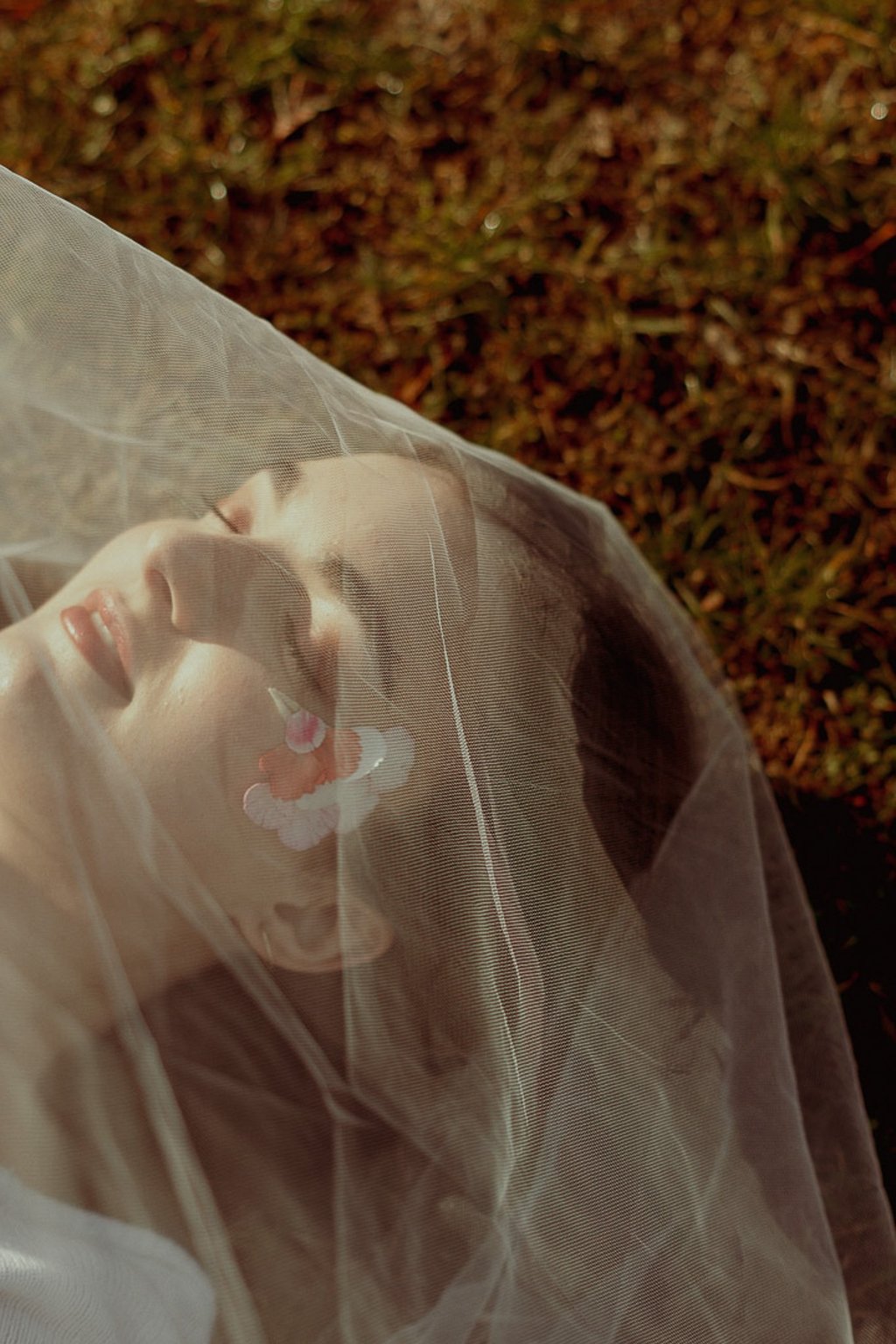 portrait rapproché d'un visage féminin maquillé recouvert d'un voile en tulle transparent