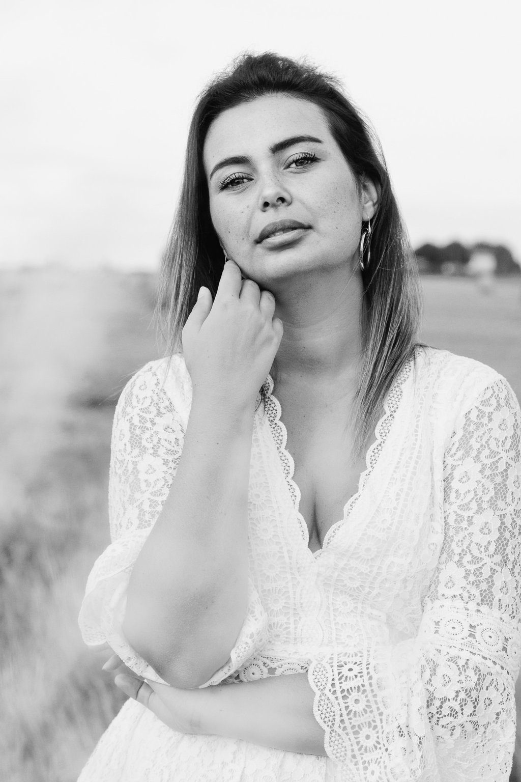 portrait féminin en noir et blanc se caressant la joue et regardant l'objectif en extérieur