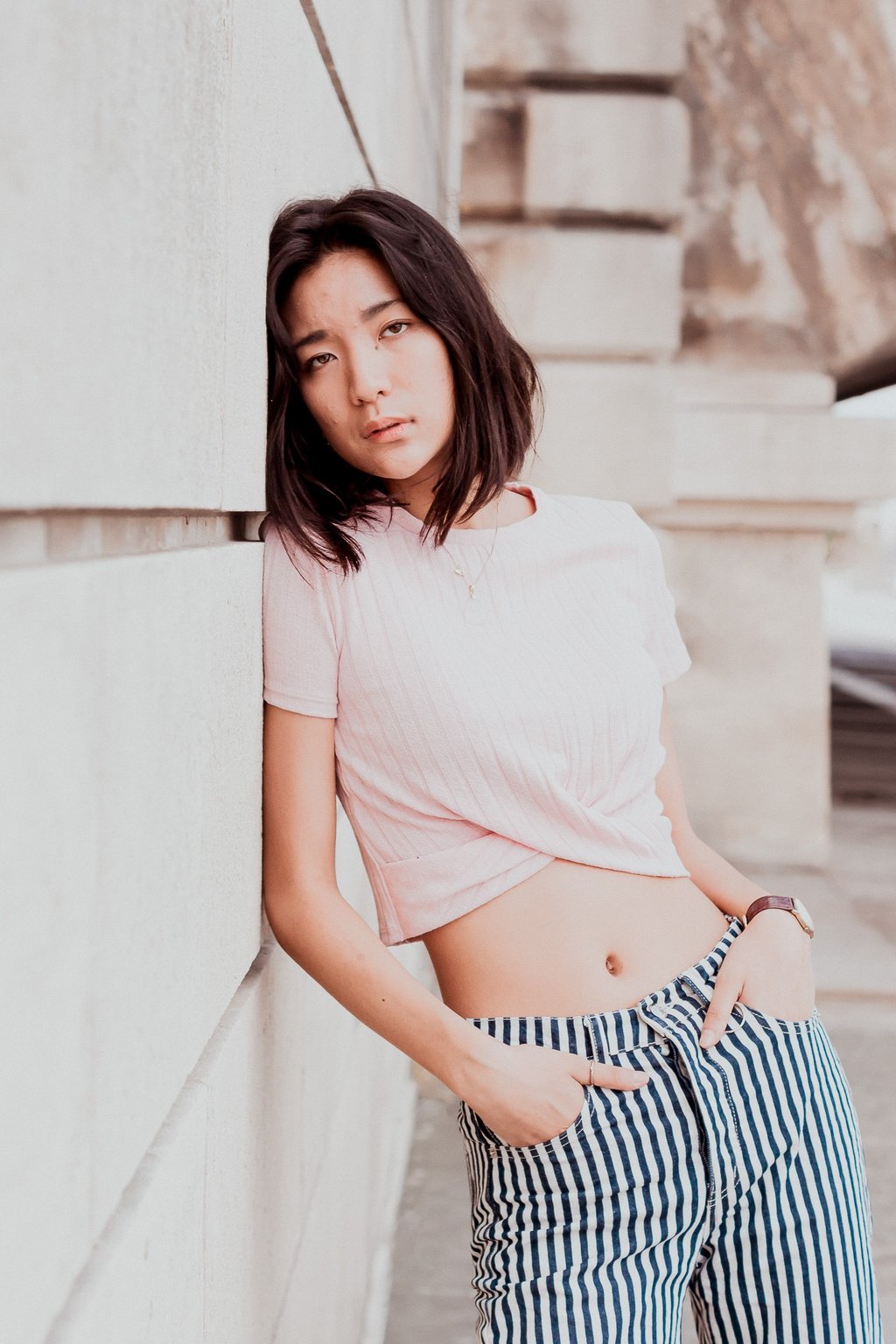 portrait de femme adossée contre un mur en pierreregardant l'objectif couleurs douces