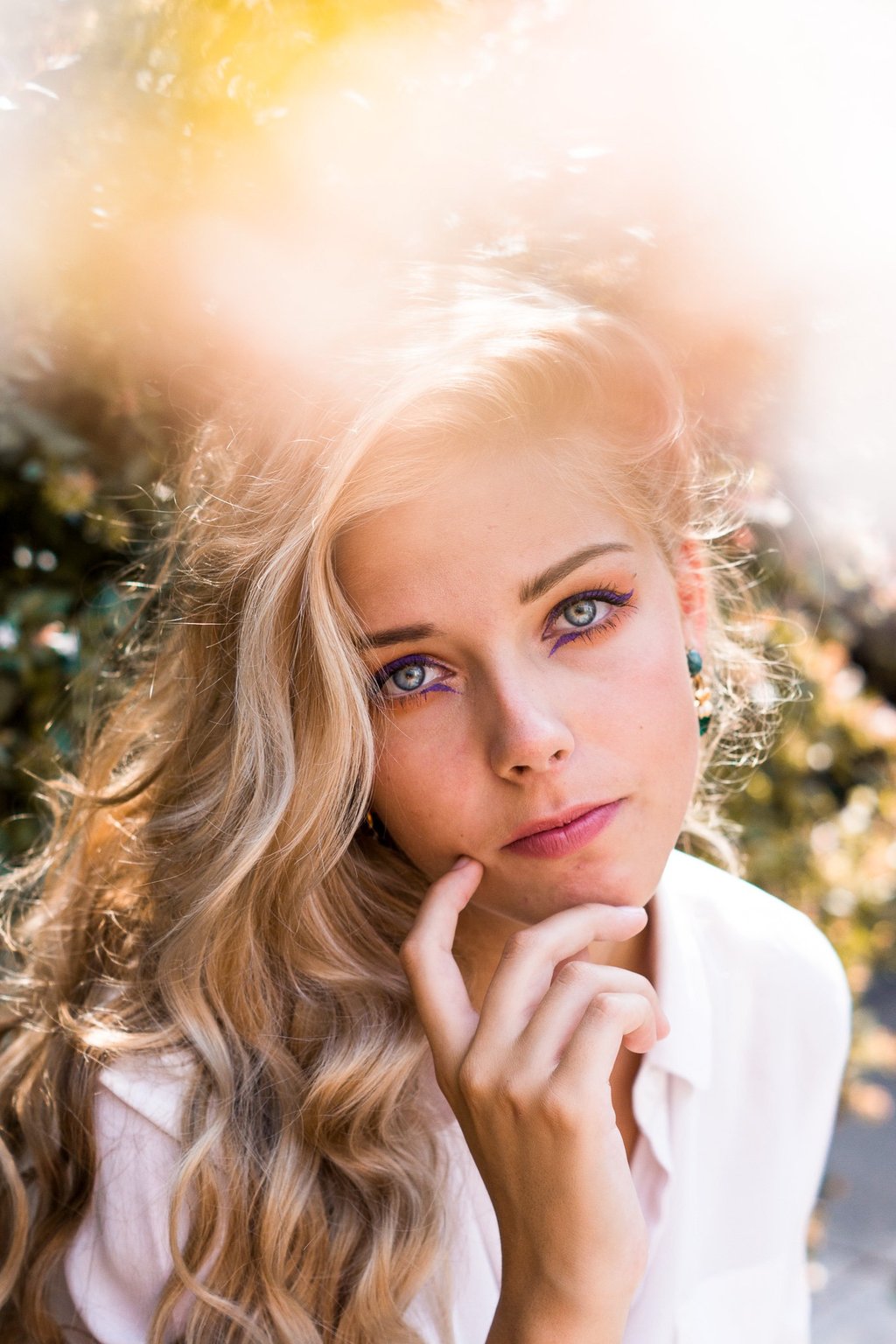portrait femme blonde aux yeux bleus portant une main sous le menton
