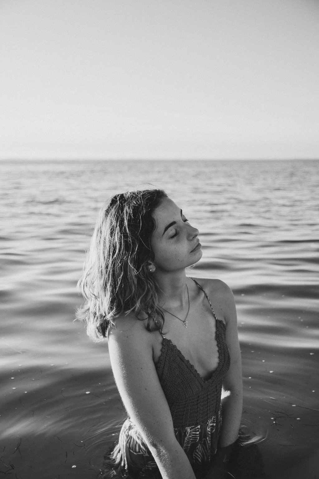 femme dans la mer jusqu'aux hanches fermant les yeux