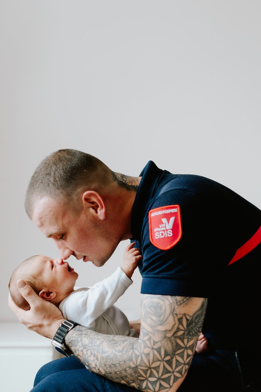 photo d'un père tenant son bébé dans les bras et collant son né au sien