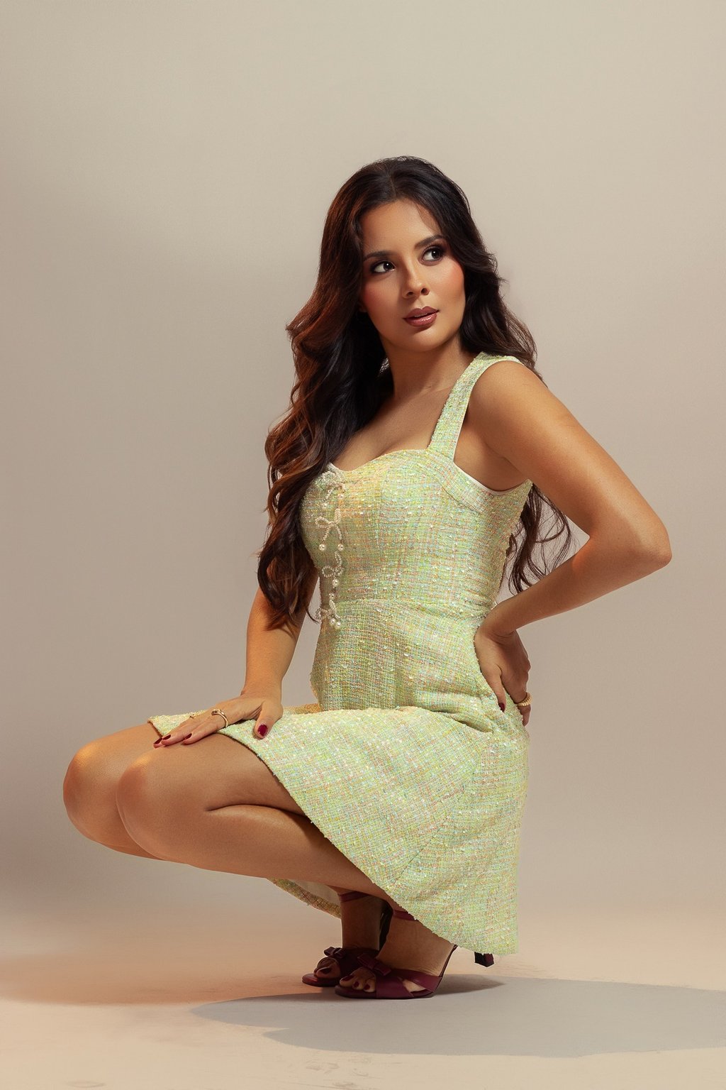 Sesión de fotos para marcas de moda en Cancún. Modelo posando en cuclillas con vestido verde e iluminación cálida.