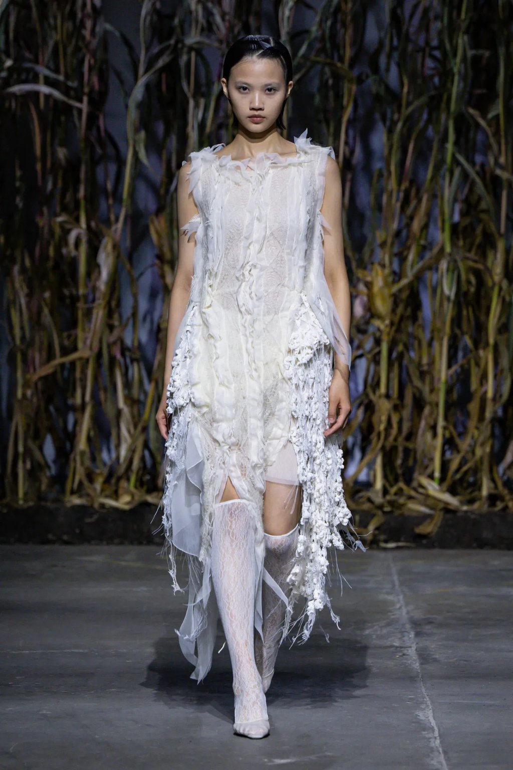 a woman in a white dress and stockings on a runway