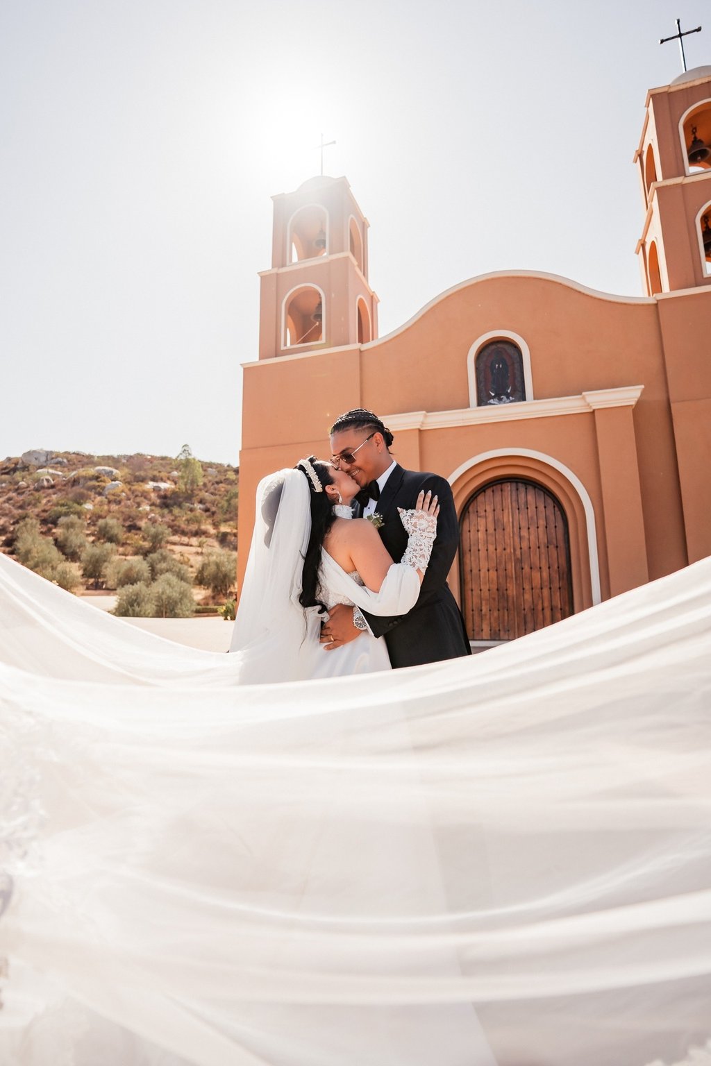 a bride and groom kissing in front of a church