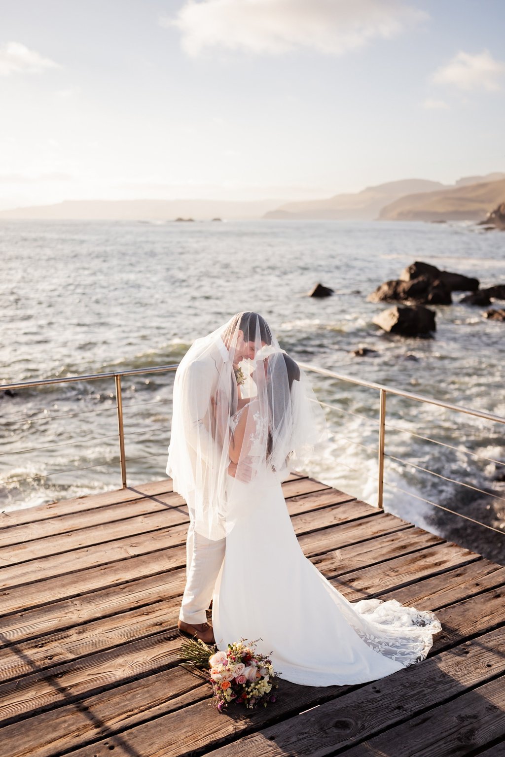 a bride and groom kissing on a pier