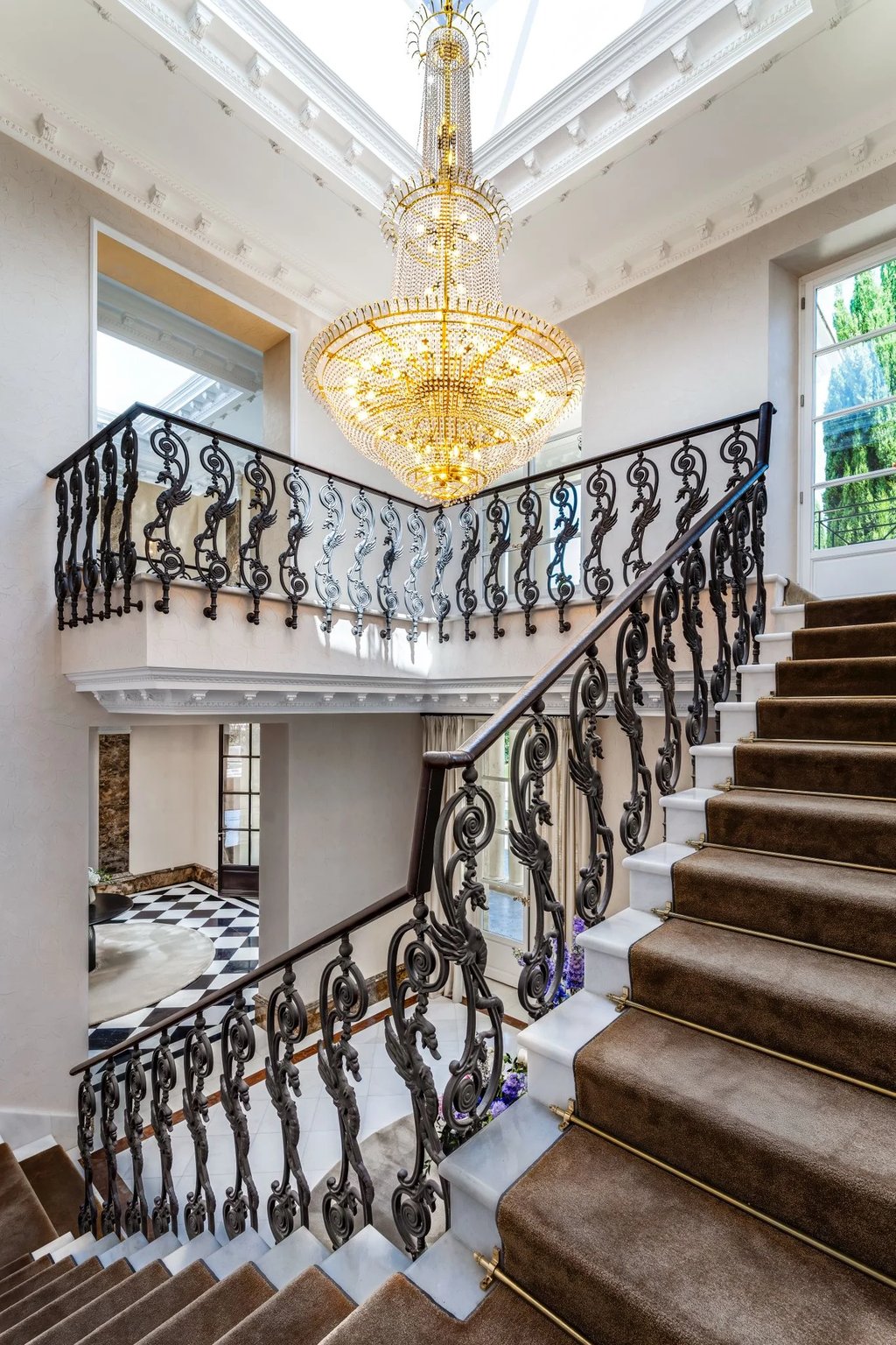 Grand staircase with ornate iron balustrade and crystal chandelier