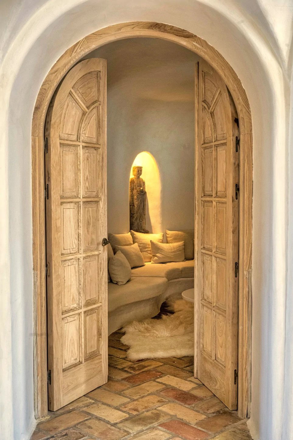 Arched wooden doors opening to intimate meditation lounge