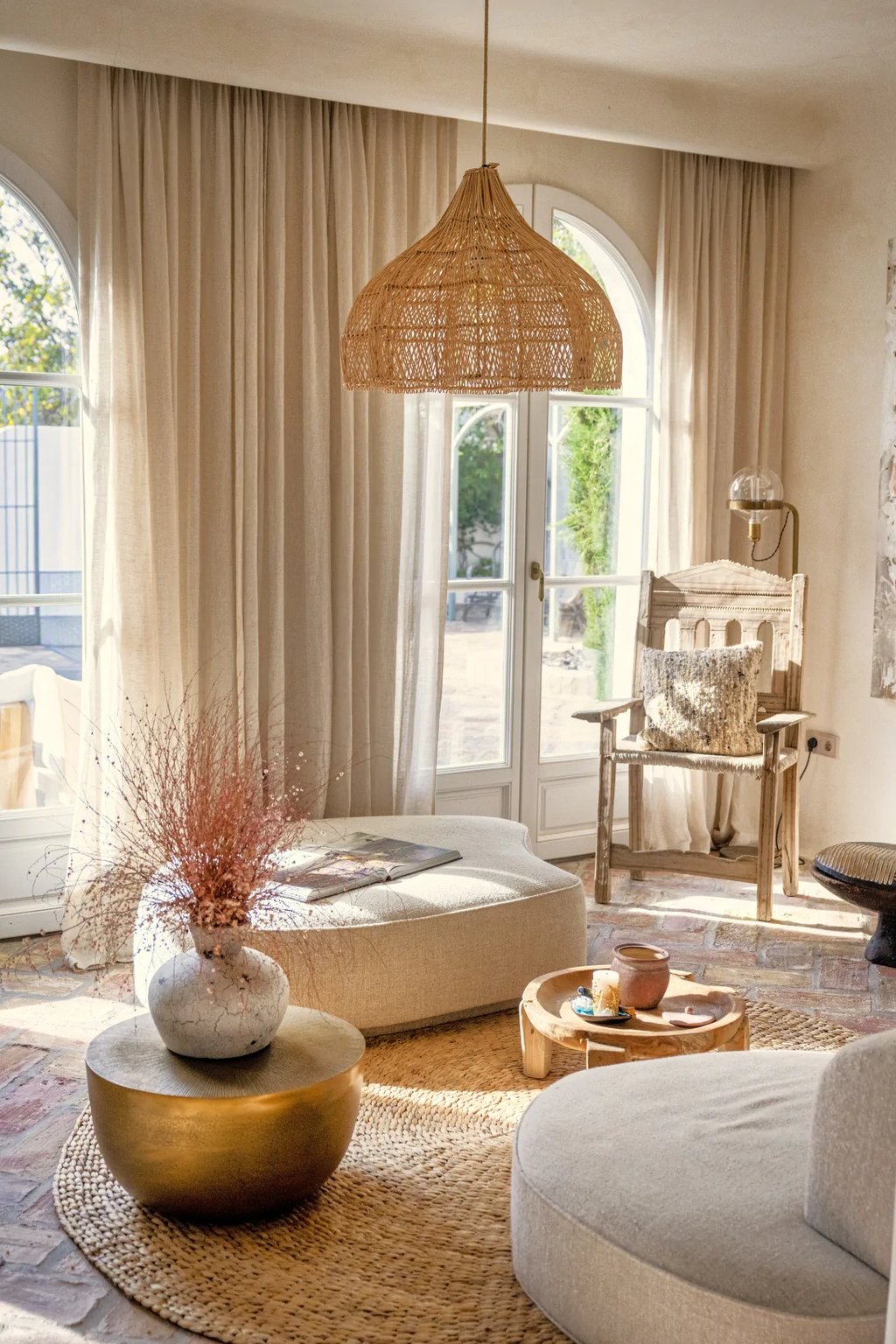 Sunlit lounge with woven pendant, arched doors and natural textures