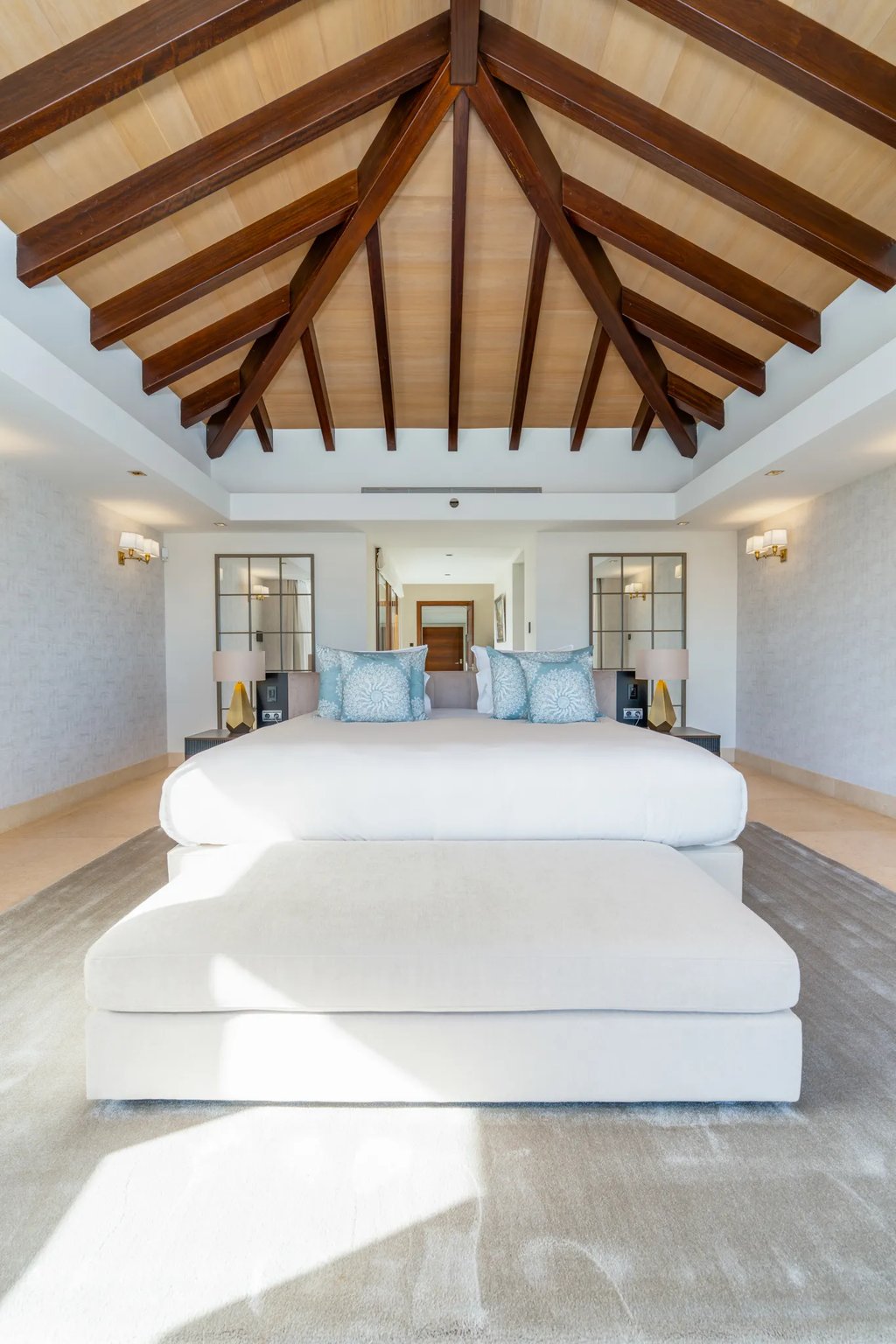 Luxury bedroom suite with a king-size bed, vaulted wood ceiling, and modern tropical decor.