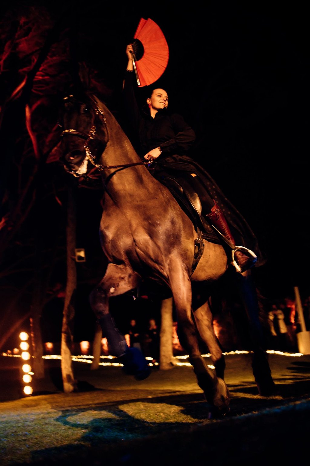 Bride on horseback with red fan at night wedding show