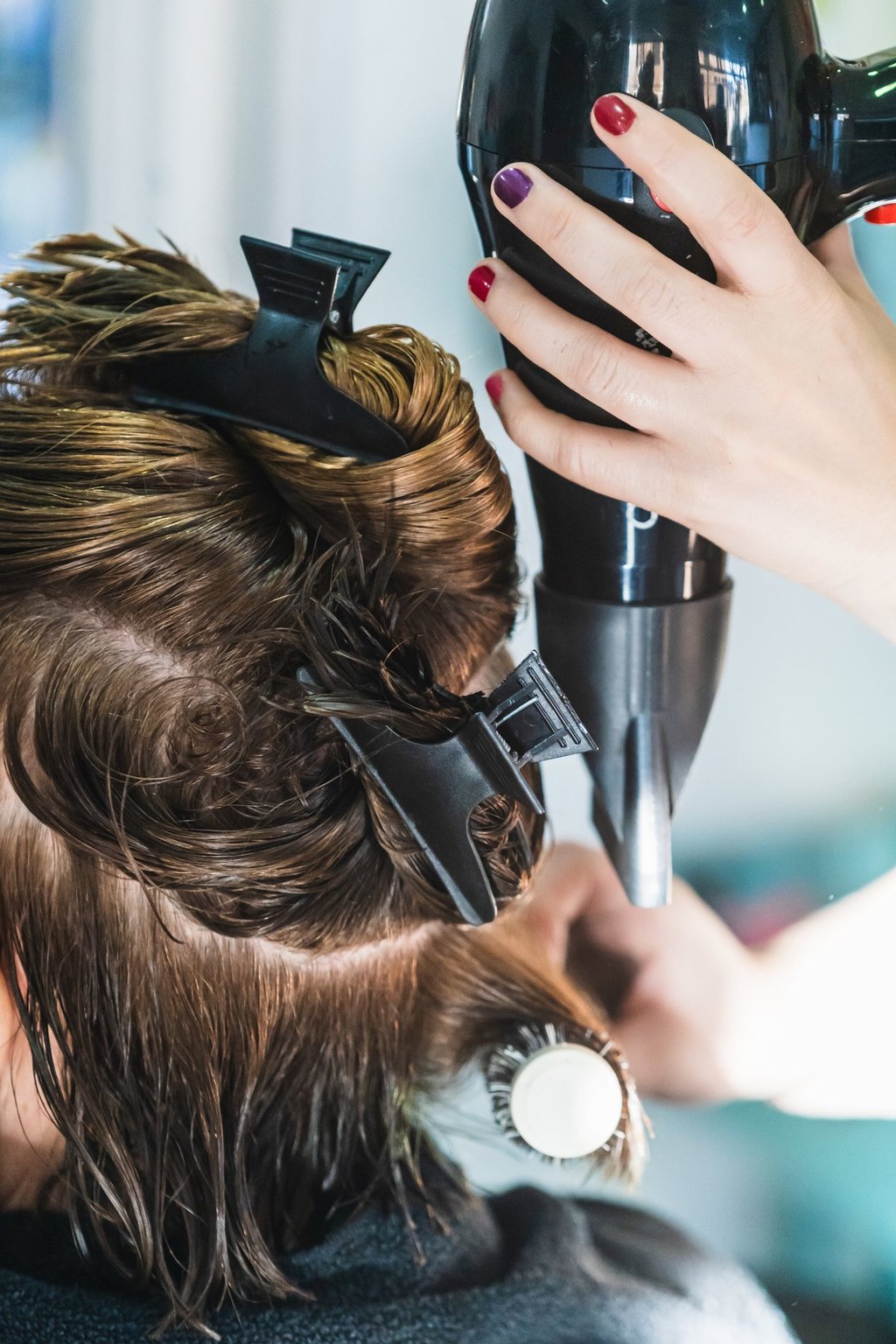 a woman is blow drying her hair in a salon