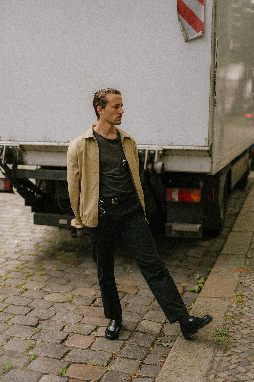portrait of artist and designer Philipp Schäfer standing on a brick sidewalk next to a truck