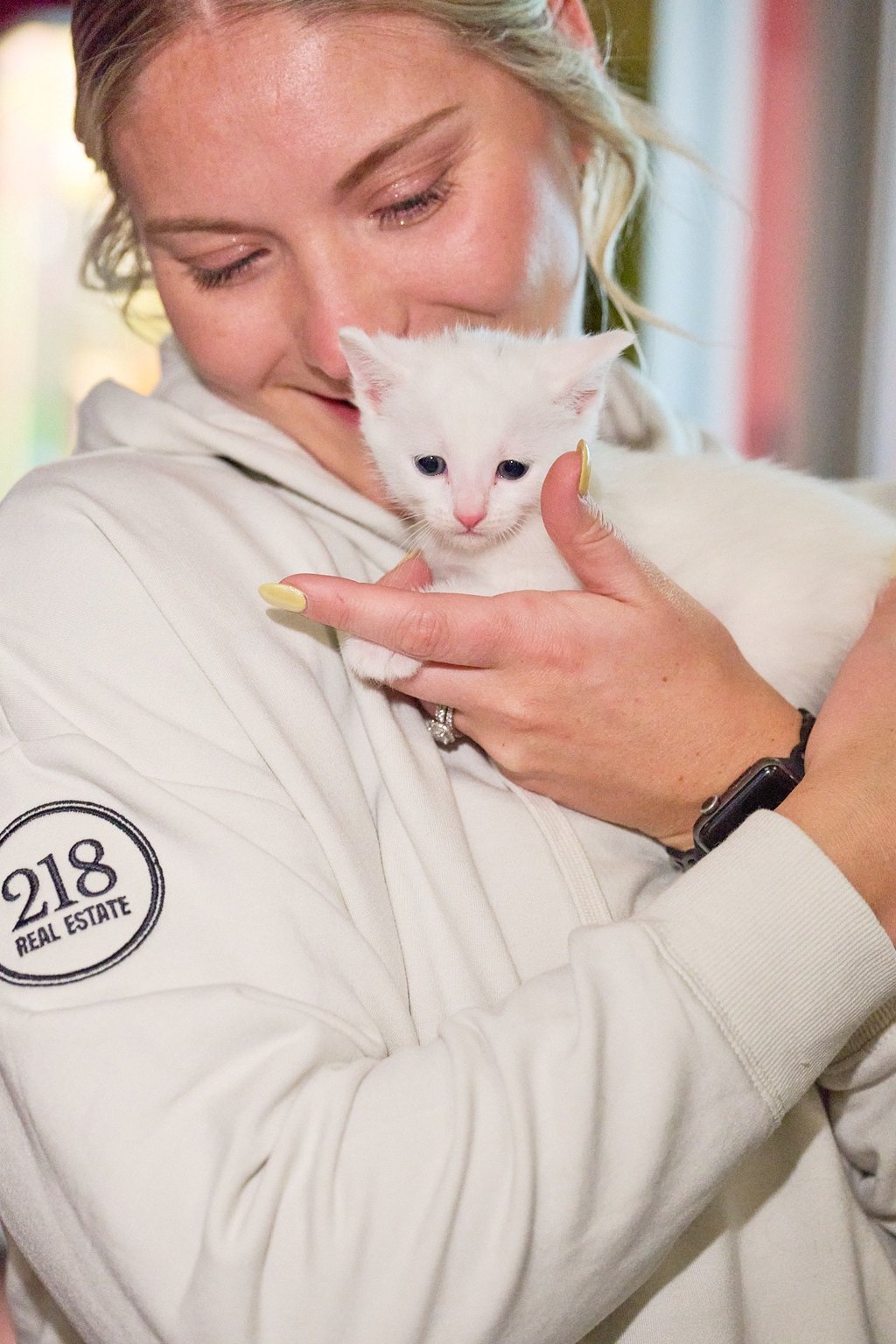 a woman holding a white kitten in her arms