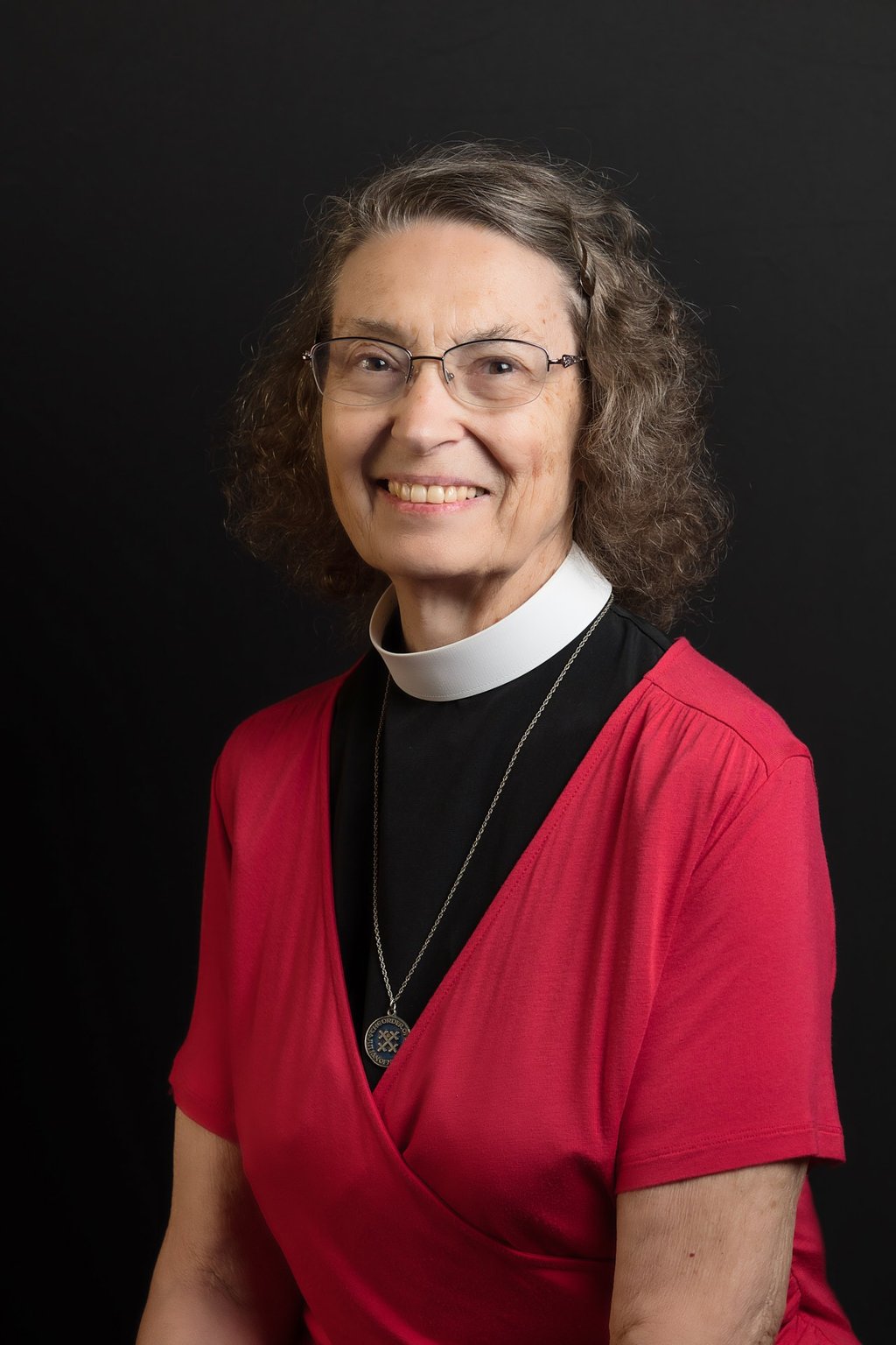 a woman in a red dress and glasses wearing a necklace