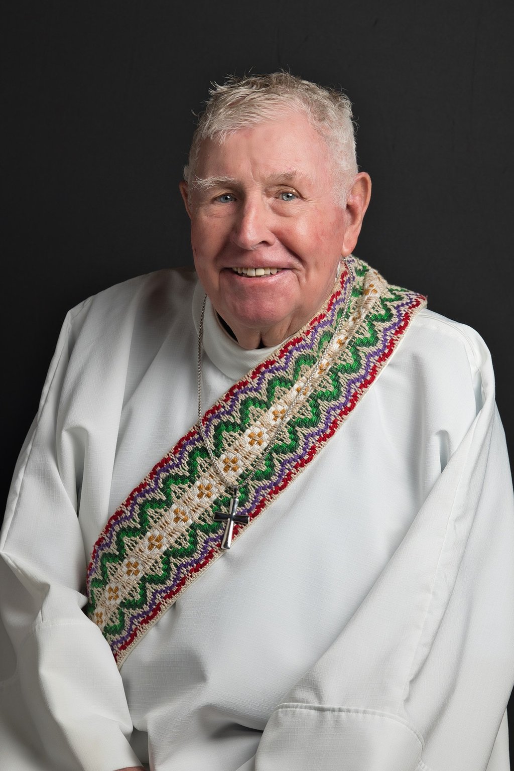a man in a white shirt of church clergy and a tie dye on his neck