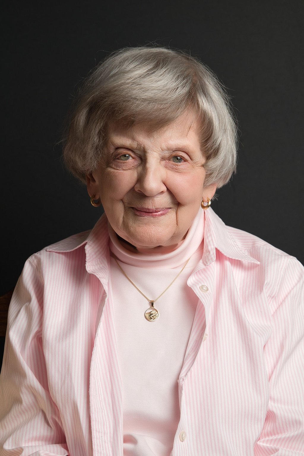 an old woman in a pink shirt and a necklace and earrings