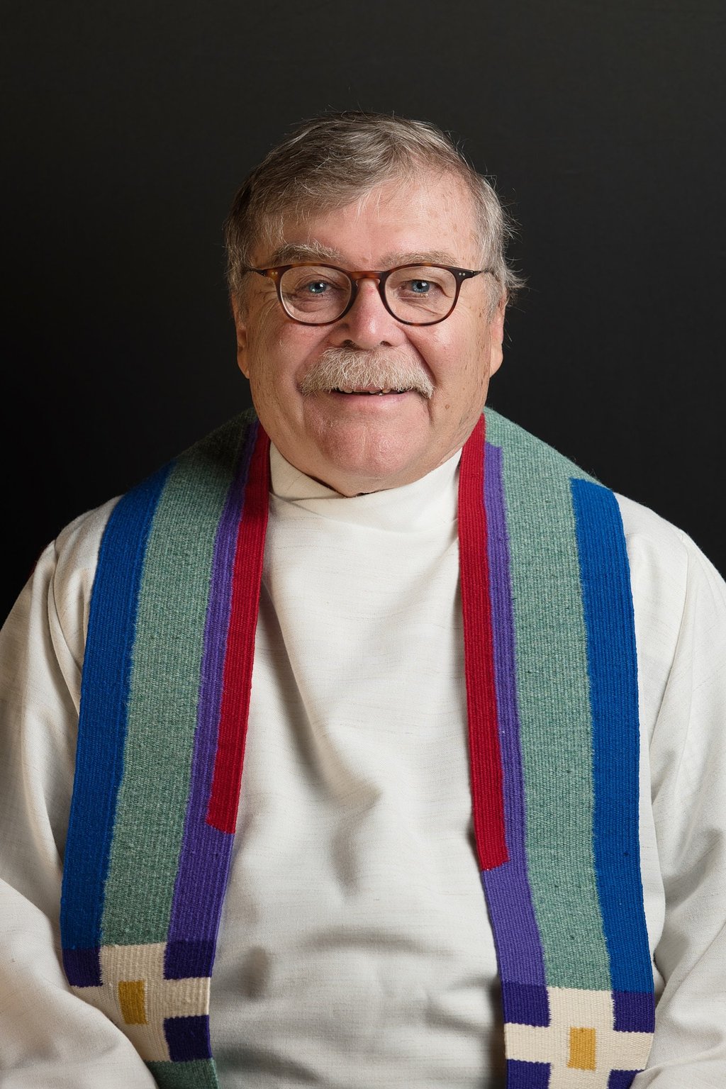 a man with beard in a priest's robes and glasses