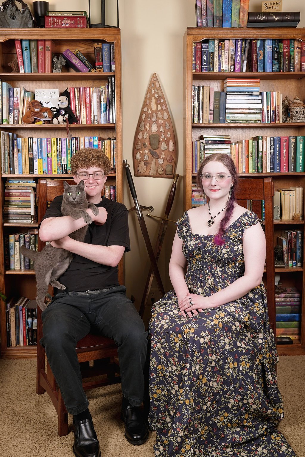 a son with a cat and a daughter sitting on a chair in a library