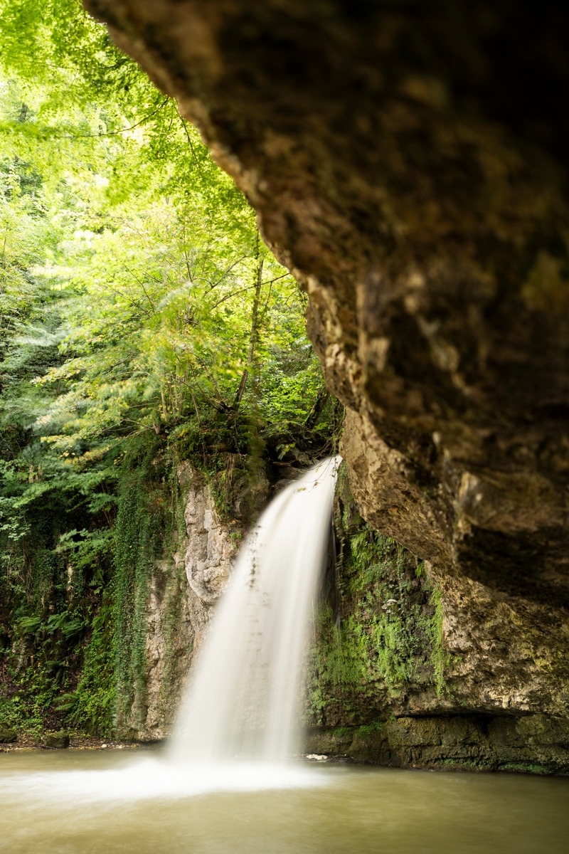a waterfall in a cave in the woods