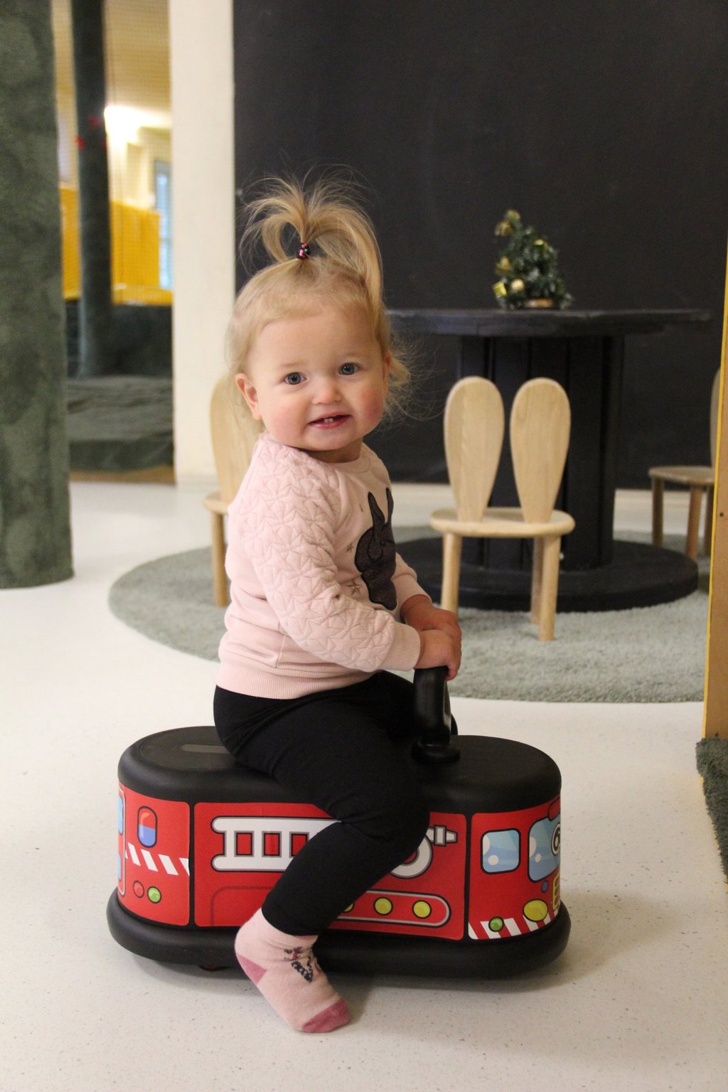 mergaite sėdi ir žaidžia su paspiriama mašinėle