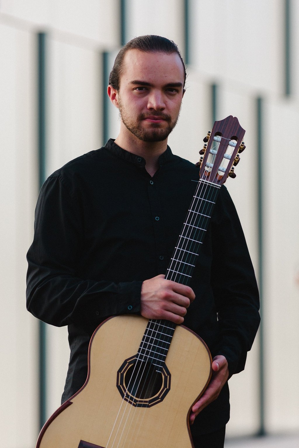 Classical guitarist Filip Babic holding guitar outside summer photo