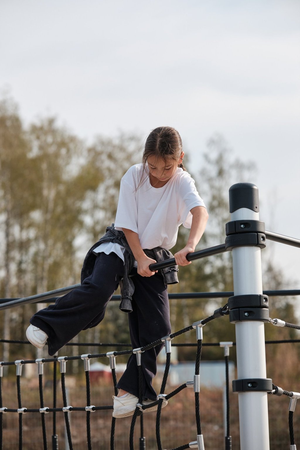 Fille grimpant sur une structure Kenguru Pro Kids Active Play en extérieur.