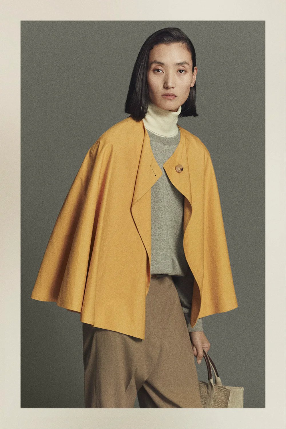 Woman wearing yellow cape jacket minimalist fashion.