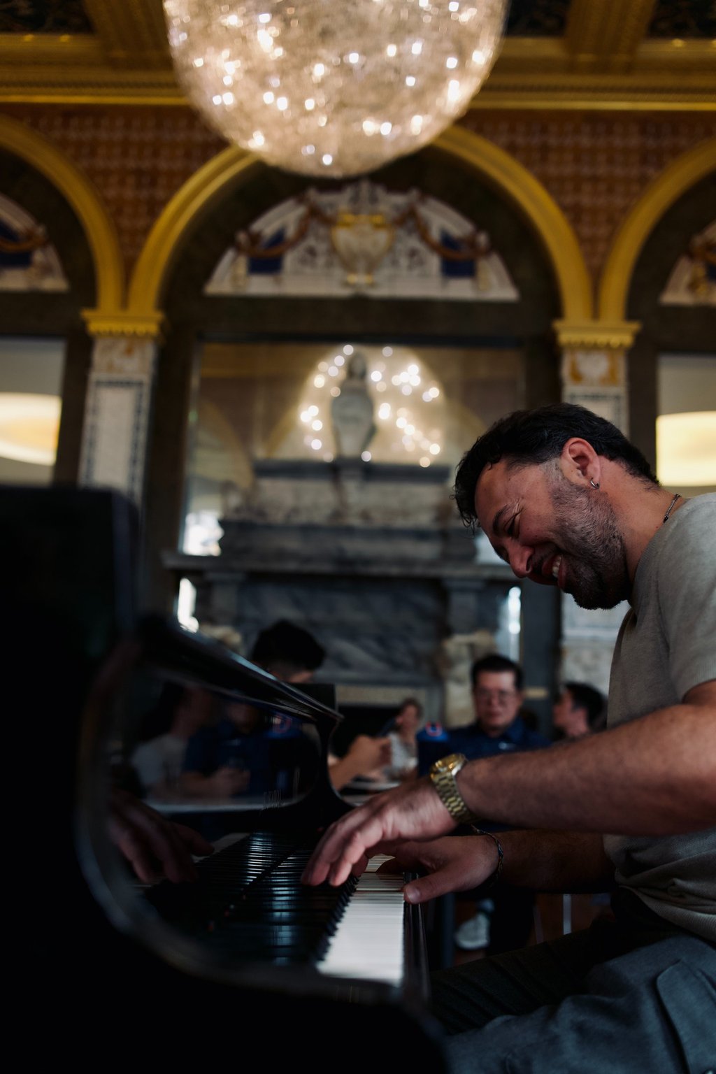 a man playing a piano in a room with a chandelier