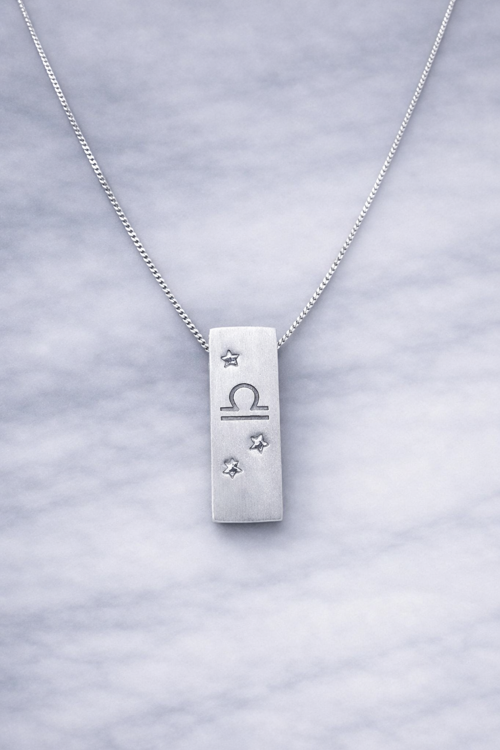 Handmade 999 silver Libra zodiac necklace with a vertical bar pendant on a marble surface.