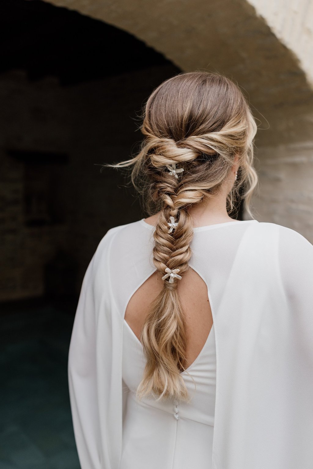 Blonde bride wearing her hair in a fishtail braid and pearl hair accessories