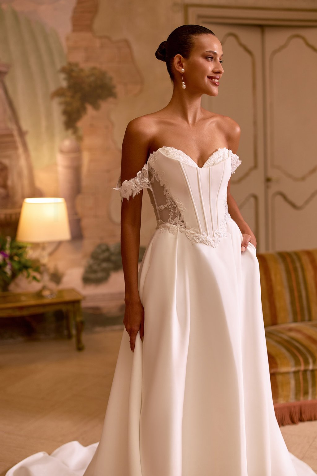 Elegant bride in a strapless corset wedding dress with off-the-shoulder lace sleeves and a full satin skirt.