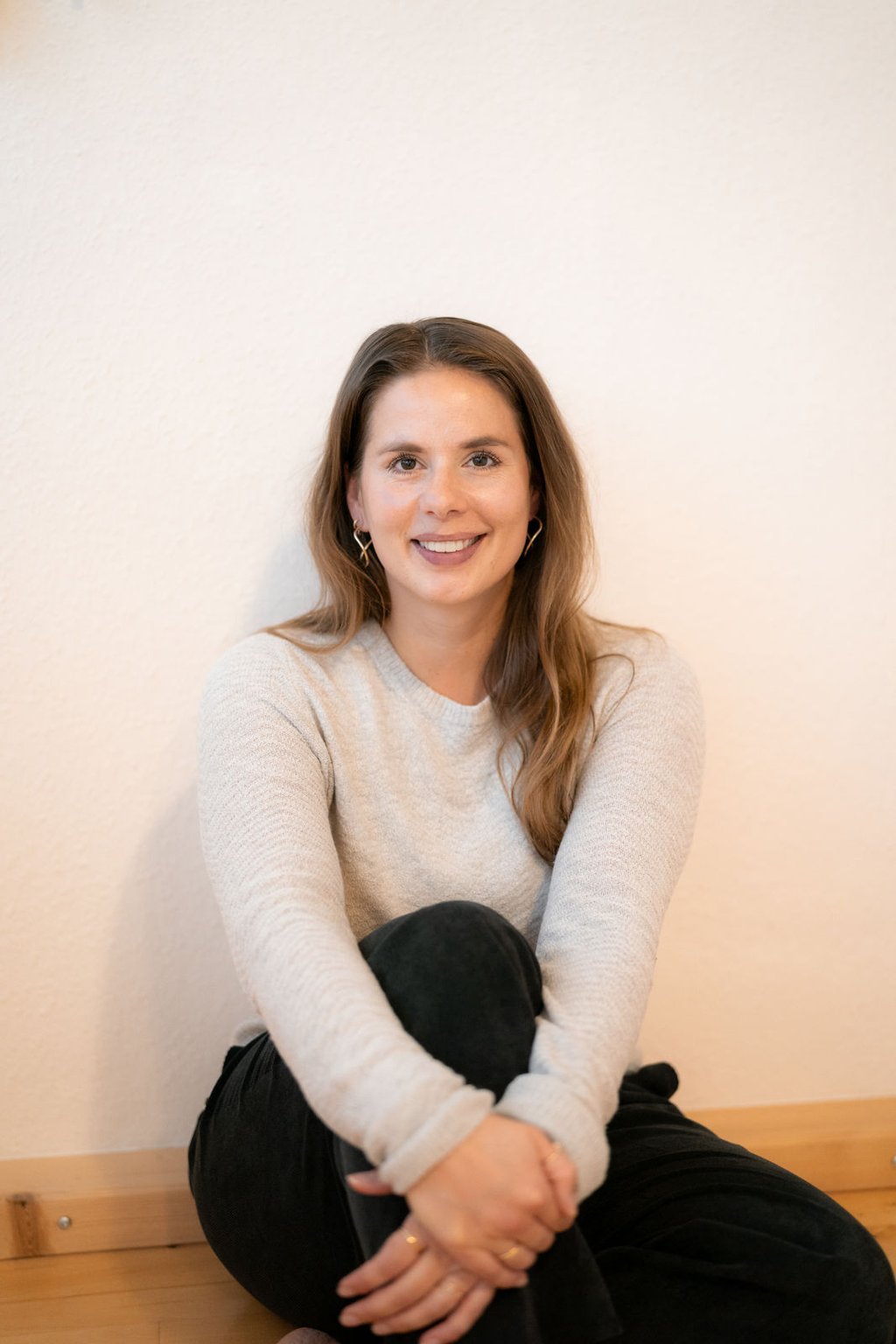 Eine Frau, mit verschränkten Beinen auf dem Boden sitzend. Stressmanagement Beratung.