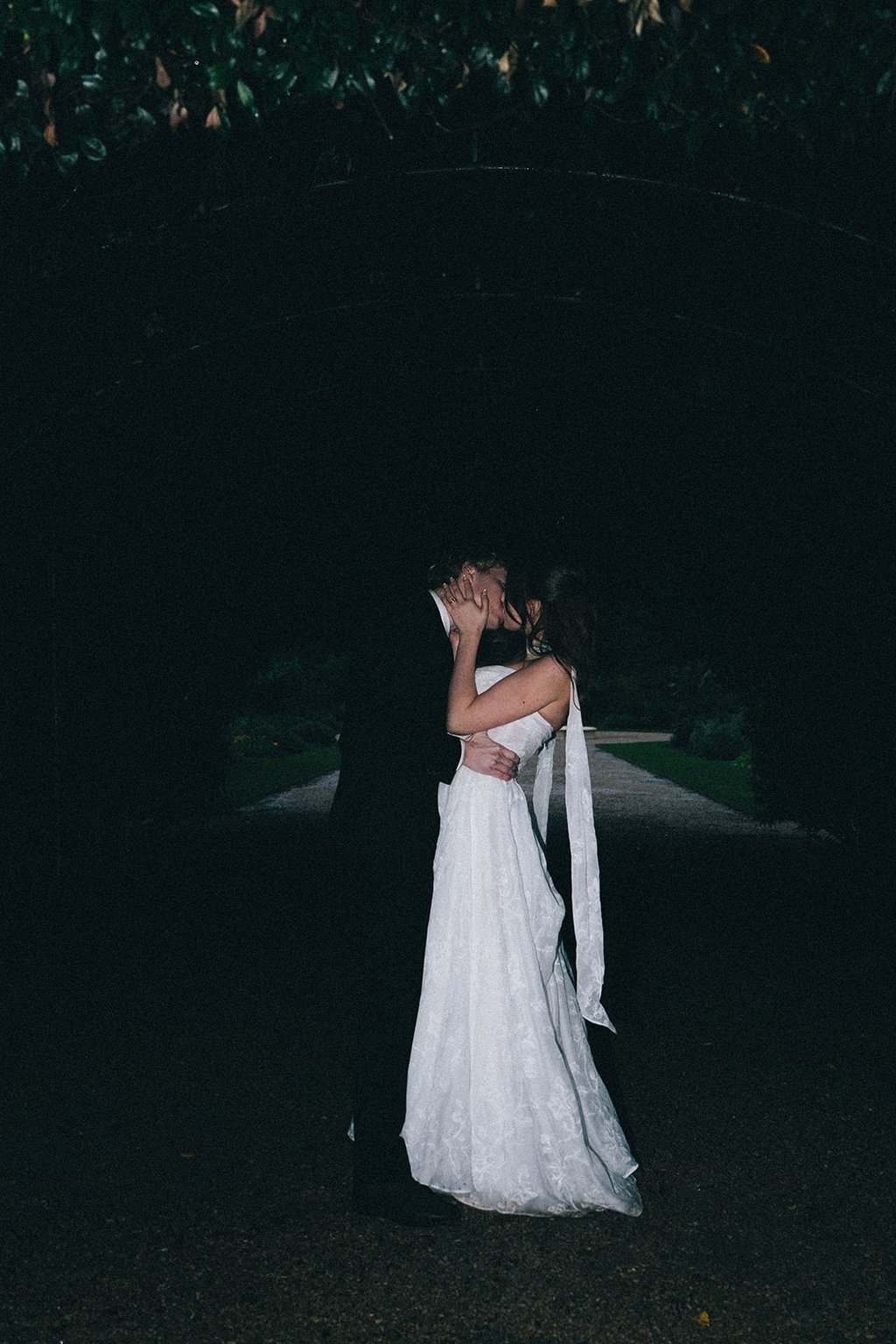 A bride and groom sharing a romantic kiss at a dark night wedding ceremony outdoors.