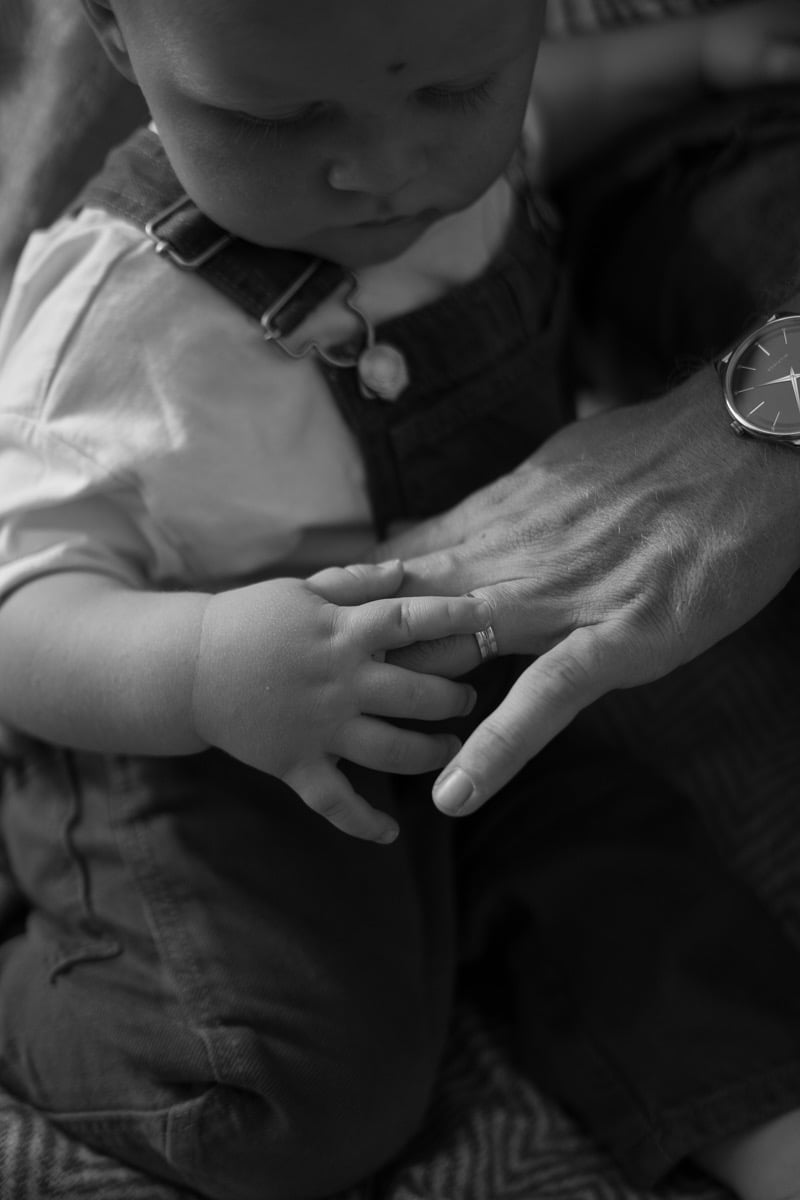 Baby boy playing with hands of his father