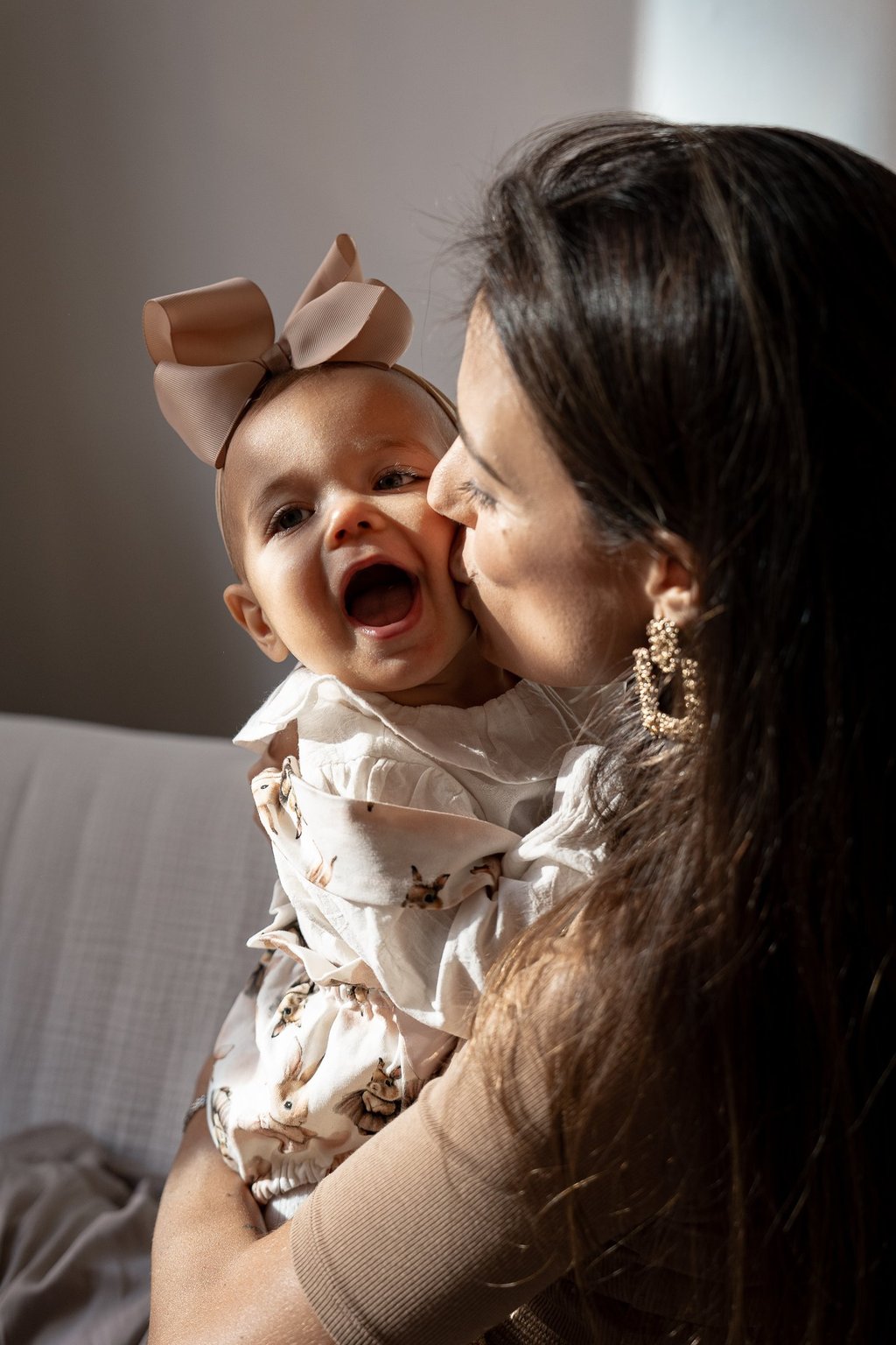 mother holding her baby on the arms and kissing baby's cheek