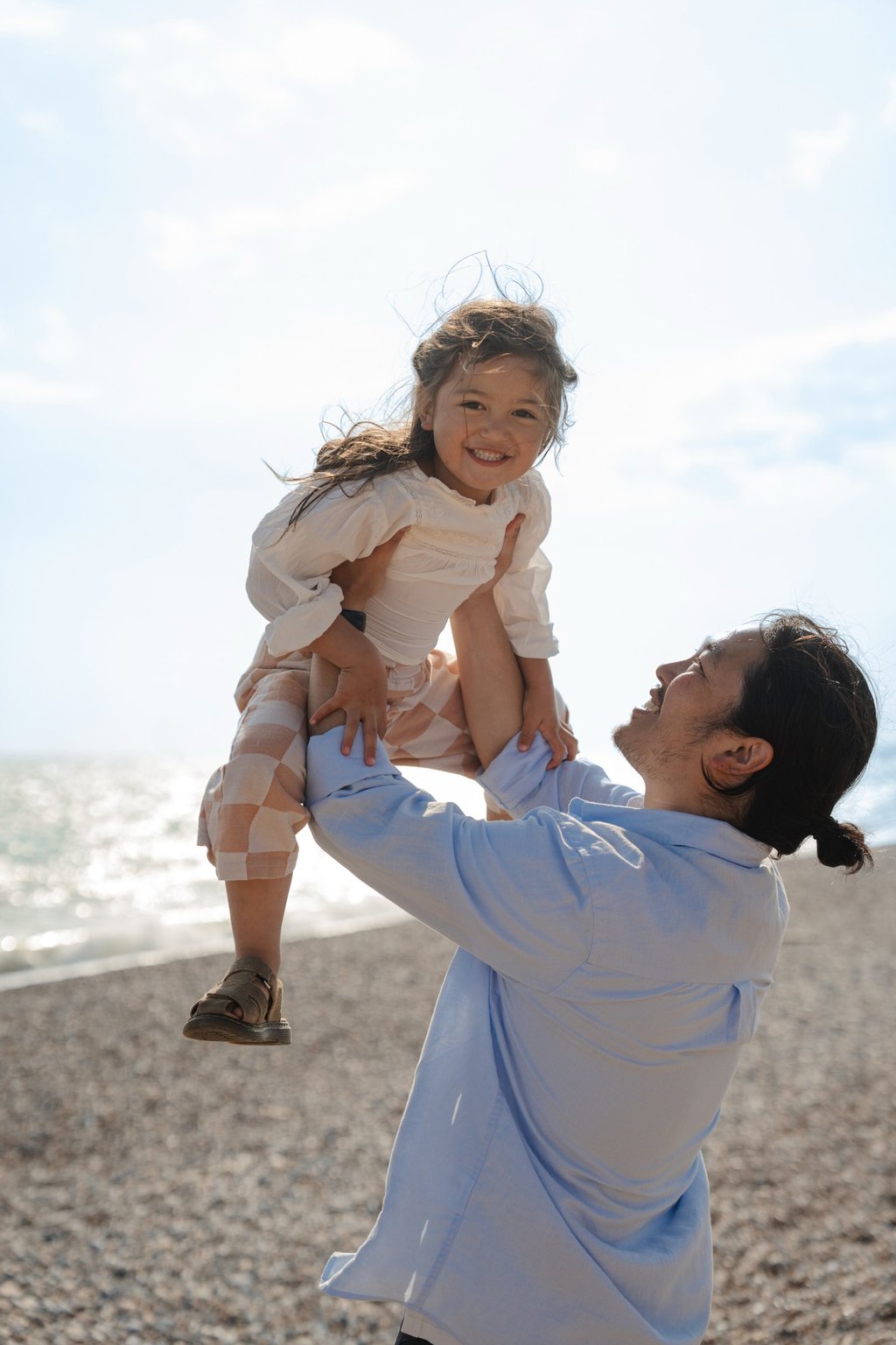 father holding her daughter up in the sky and girl is smiling