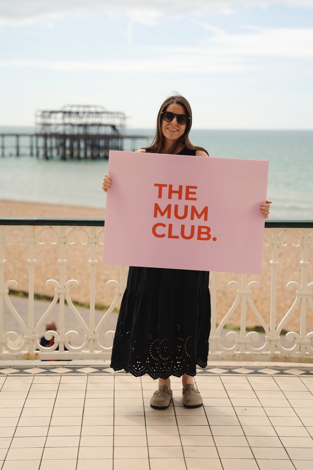 woman smiling holding a big sign on the seafront