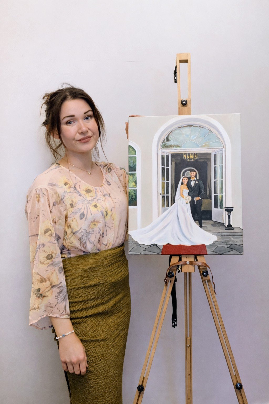 Christine live wedding painter standing beside a finished wedding painting on an easel