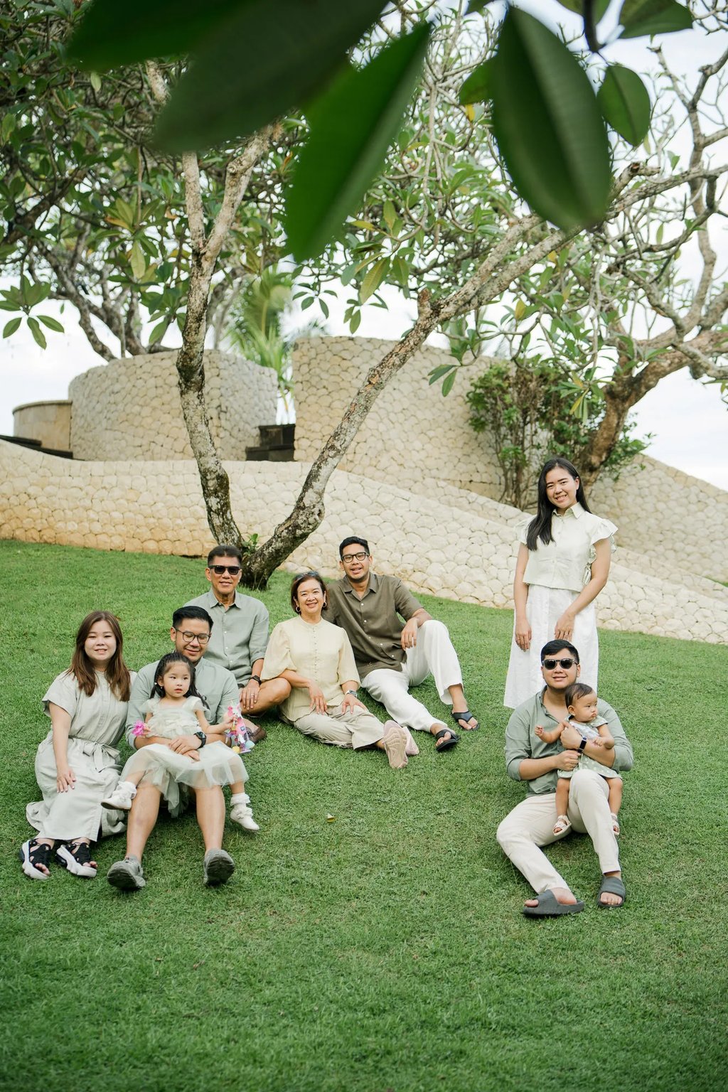 Large family enjoying time together in a tropical garden during a Bali family photography session.
