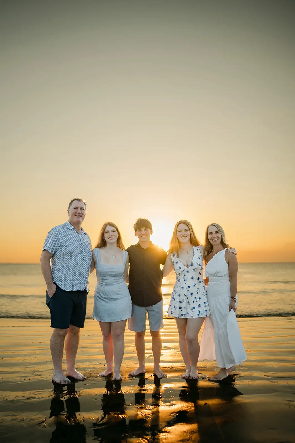 Family standing together on Jimbaran Beach during a relaxed sunset photography session in Bali