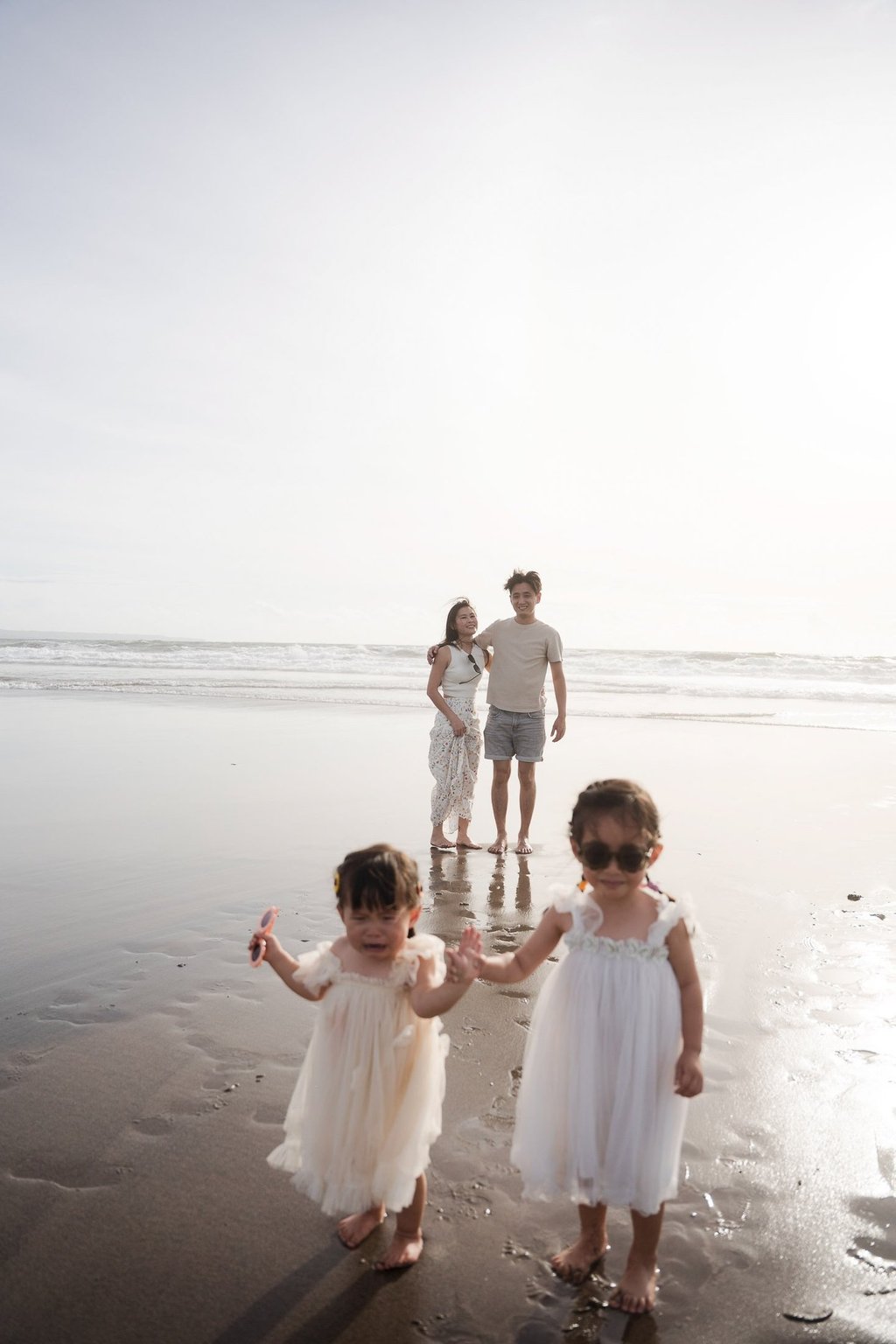 Family walking  along the shoreline at Petitenget Beach Seminyak Bali during a relaxed lifestyle family photography session